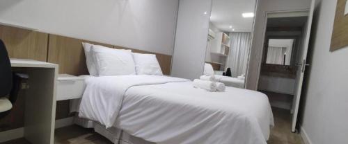 Schlafzimmer mit einem weißen Bett und einem Spiegel in der Unterkunft Flat em Tambaú 50m da praia in João Pessoa