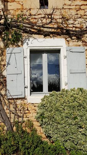 a window on a stone building with a bush in front of it at Le Marais in Chasseneuil-sur-Bonnieure