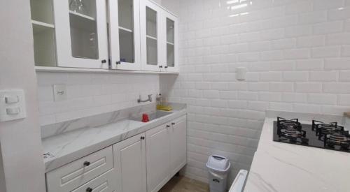- une cuisine blanche avec évier et cuisinière dans l'établissement Flat em Tambaú 50m da praia, à João Pessoa