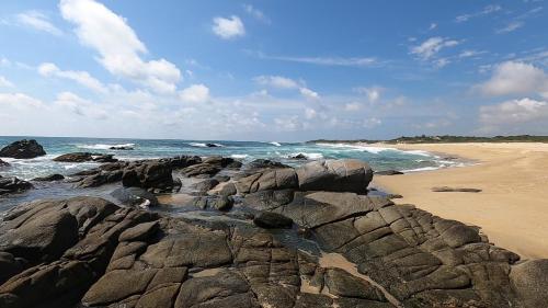 a beach with rocks and the ocean on a sunny day at OCEAN OASIS HOTEL - adult only, four casitas boutique resort in Playa Agua Blanca