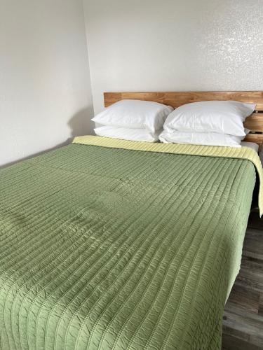 1 cama con edredón verde y 2 almohadas en Coastal Lodging en Seward