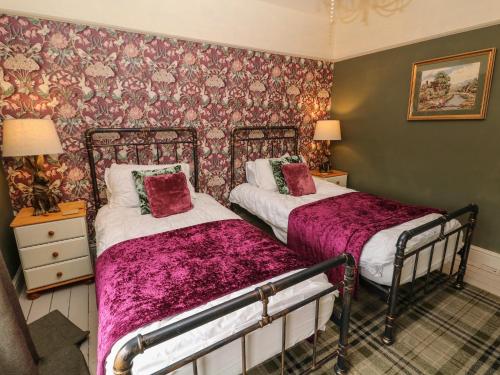 two beds in a room with floral wallpaper at Liberty House in Ashbourne