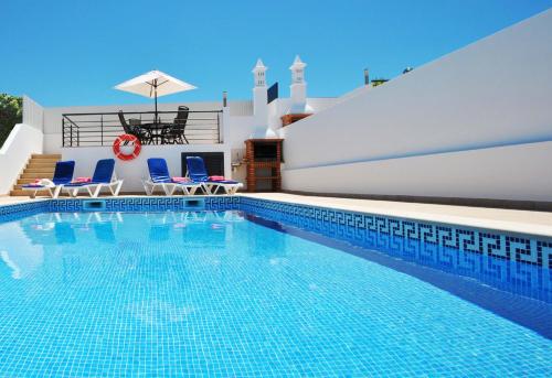 een zwembad met 2 stoelen en een parasol bij Villa Antiqua by Algarve Vacation in Albufeira