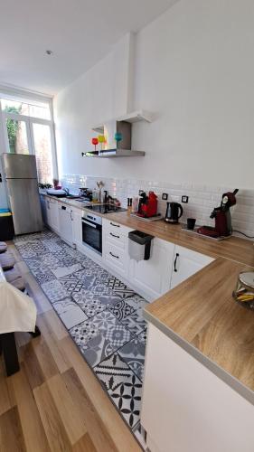 uma grande cozinha com armários brancos e um tapete em Maison de charme, coeur de Douai em Douai