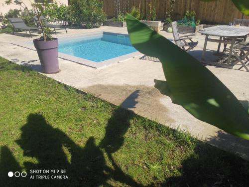 une ombre d'une personne debout devant une piscine dans l'établissement Maison entre océan et bordeaux, à Le Taillan-Médoc