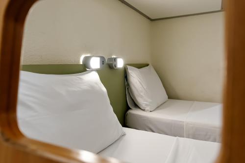 a small room with two beds and a mirror at ibis budget Vitoria in Vitória