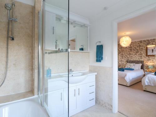 een badkamer met een wastafel, een douche en een bed bij Hedgefield House in Grantham
