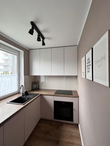 a kitchen with white cabinets and a sink and a window at Apartament Przy Obserwatorium&Singielnia in Olsztyn
