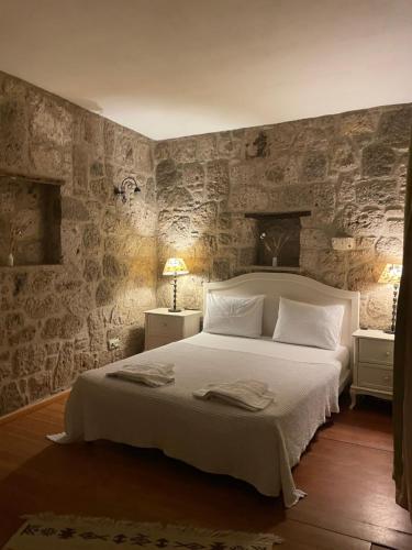 a bedroom with a white bed with stone walls at MaSaLa Otel in Alacati