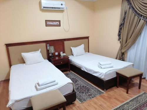 2 camas individuales en una habitación con ventana en Sarbon Plaza Hotel, en Bukhara