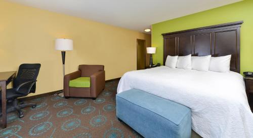 a hotel room with a large bed and a chair at Hampton Inn Iowa City/University Area in Iowa City