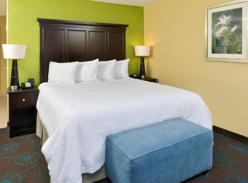 a bedroom with a large bed with a blue ottoman at Hampton Inn Iowa City/University Area in Iowa City