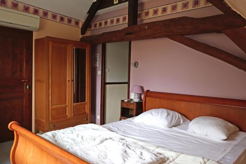 une chambre avec un grand lit avec une tête de lit en bois dans l'établissement Corbon, à Vivoin