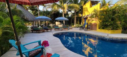 a swimming pool with chairs and umbrellas next to a resort at OCEAN OASIS HOTEL - adult only, four casitas boutique resort in Playa Agua Blanca