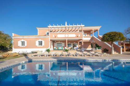 a villa with a swimming pool in front of a house at Al Meida Guesthouse in Albufeira