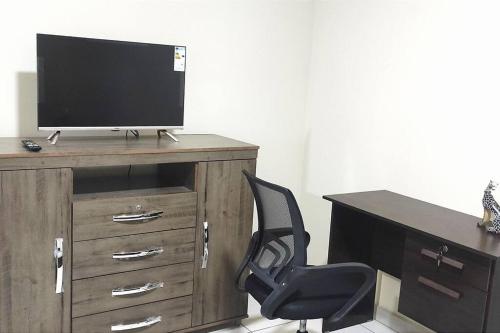 escritorio con silla y armario de madera con TV en Céntrico Estudio Cruceño A/C 2, en Santa Cruz de la Sierra