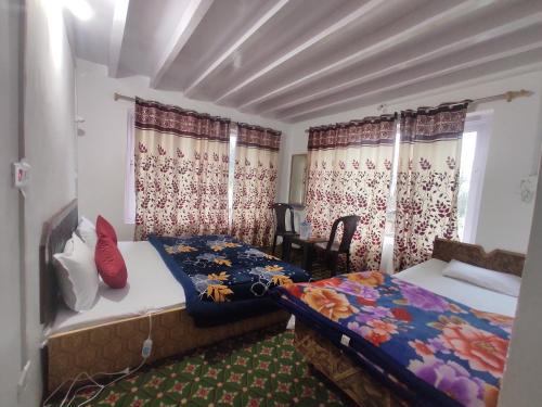 a bedroom with two beds and a window with curtains at Betab Valley Guest House Pahalgam in Pahalgām