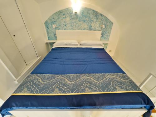 a bed in a small room with a blue wall at Alfieri Rooms - Amalfi coast in Atrani