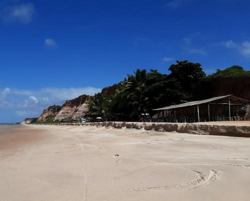a sandy beach with trees and a building on it at Hostel Summer Praia do Sol in João Pessoa