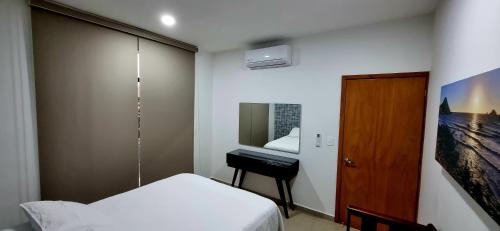 a small bedroom with a bed and a desk at Confortable Departamento in Mazatlán