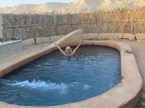 a woman holding a surfboard in a swimming pool at Beir El Gabal Hotel (with Hot Springs) in Al Qaşr