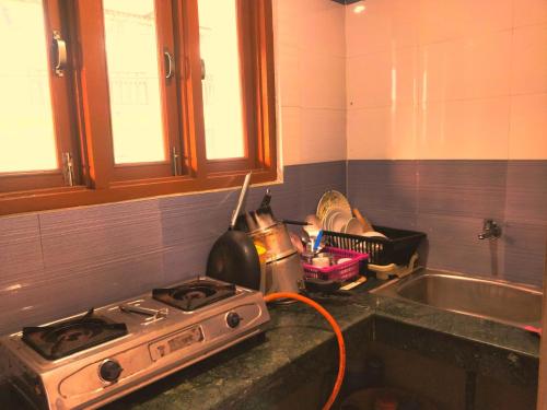 a kitchen with a stove and a sink at The Kashi Baba Homestay in Dharamshala