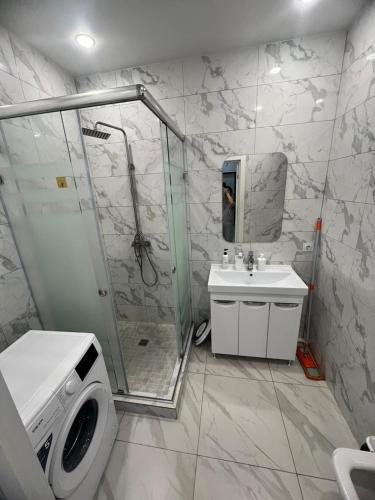 een badkamer met een douche, een wastafel en een wasmachine bij Nureke Apartment's in Alma-Ata