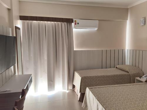 a hotel room with two beds and a window at Spazio DiRoma com Acesso ao Acqua parque in Caldas Novas