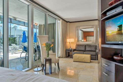 Habitación de hotel con TV y sala de estar. en Boutique Suites 3 min walk to beach en Miami Beach