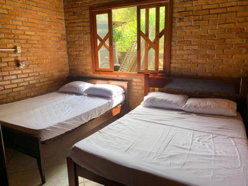 two beds in a room with two windows at Sítio com piscina incrível in Santo Amaro da Imperatriz