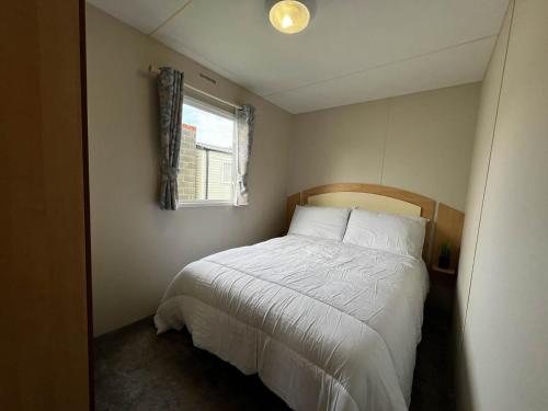 a small bedroom with a bed and a window at Lovely 8 Berth Caravan At Highfield Grange In Essex Ref 26213o in Clacton-on-Sea