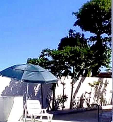 a blue umbrella and a white chair and a chair and a table at Hostel Summer Praia do Sol in João Pessoa