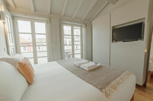 a bedroom with a white bed with a flat screen tv at Deluxe Duplex by Hosty in Porto