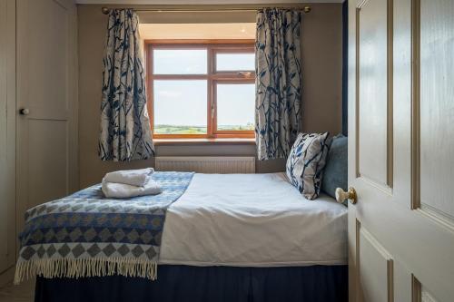 a small bedroom with a bed with a window at Blaenachddu in Capel-Ifan