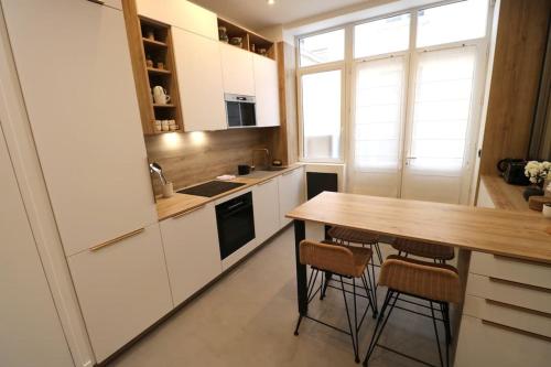 une cuisine avec des armoires blanches et une table en bois dans l'établissement Cosy 2 chambres / Père-Lachaise, à Paris