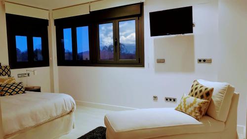 1 dormitorio con 1 cama, 1 silla y ventanas en Vivienda Vacacional La Talima, en La Pereda de Llanes