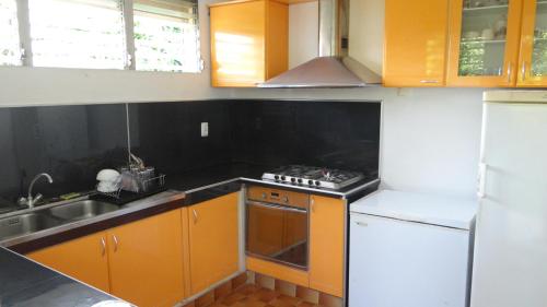 a kitchen with orange cabinets and a stove top oven at Villa Montjoly in Le Morne-Vert
