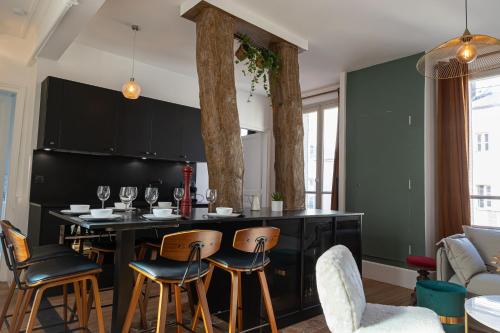 une cuisine avec un îlot noir et des tabourets de bar dans l'établissement Appartement historique cœur de ville, chic et cosy, à Rambouillet