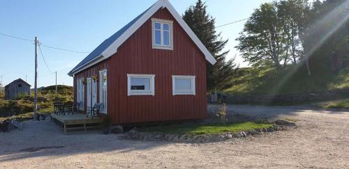 a red house with a bench in front of it at Cabin in Borgvåg Lofoten - Large in Straum