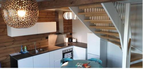 a kitchen with white cabinets and a spiral staircase at Cabin in Borgvåg Lofoten - Large in Straum