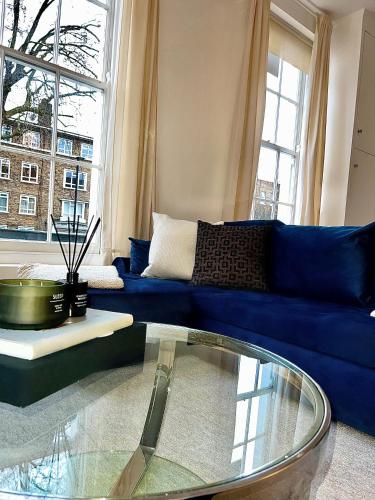 a living room with a blue couch and a glass table at Stylish One Bedroom Apartment in the heart of Angel in London