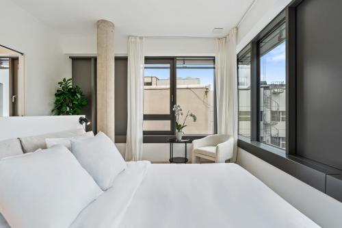 een slaapkamer met een wit bed en een groot raam bij Elegant 2BR with Balcony in Heart of Luxembourg in Luxemburg