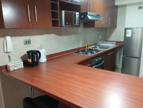 a kitchen with a wooden counter top and a refrigerator at Apartamento en Iquique in Iquique