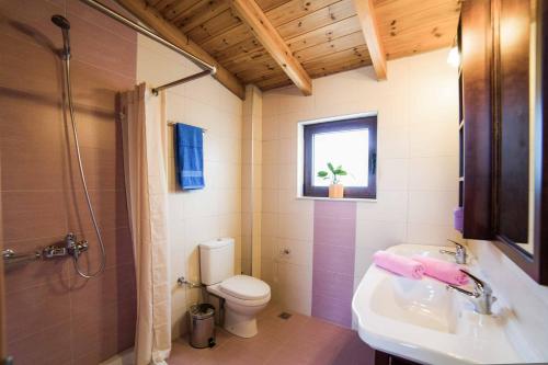 een badkamer met een wastafel, een toilet en een raam bij Villa Lemonia Platanias in Plataniás
