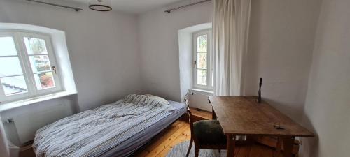 a bedroom with a bed and a desk and two windows at Ferienhaus Feinhype in Longuich