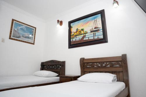 2 letti in una camera con un dipinto sul muro di Hotel La Casa Del Viajero a Cartagena de Indias