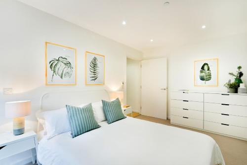 1 dormitorio blanco con 1 cama blanca y 2 almohadas en Madison Hill - Clapham South 1 - Two bedroom flat, en Londres