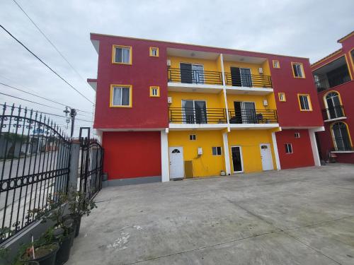a red and yellow apartment building with a parking lot at Departamentos velasco Planta baja in Tijuana