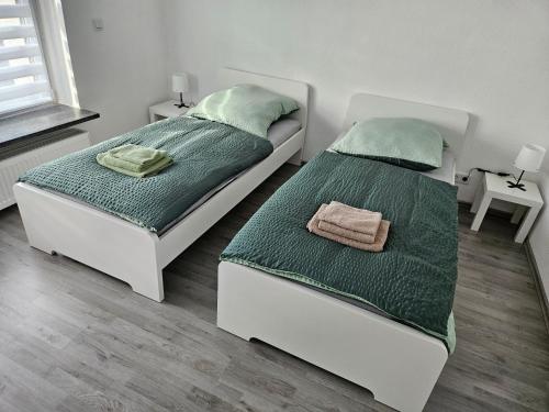 two beds in a bedroom with green sheets at An der Dorfeiche in Hamm