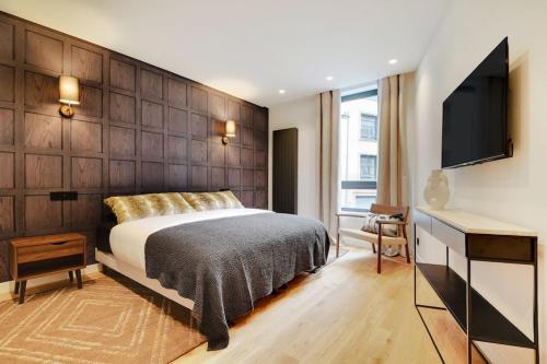 une chambre avec un lit et un bureau avec une télévision dans l'établissement Appartement de Luxe 2BDR/7P - Louvre/tuileries, à Paris